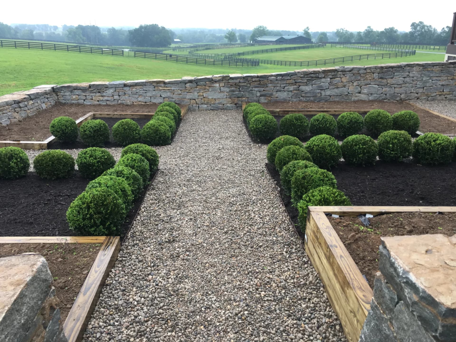 Finished Lexington walkway with shrub planting and wood-framed garden beds beside a home