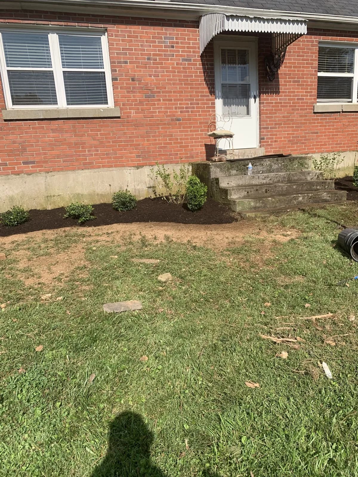 Finished foundation shrub bed with fresh mulch beside a Paris, Kentucky farmhouse