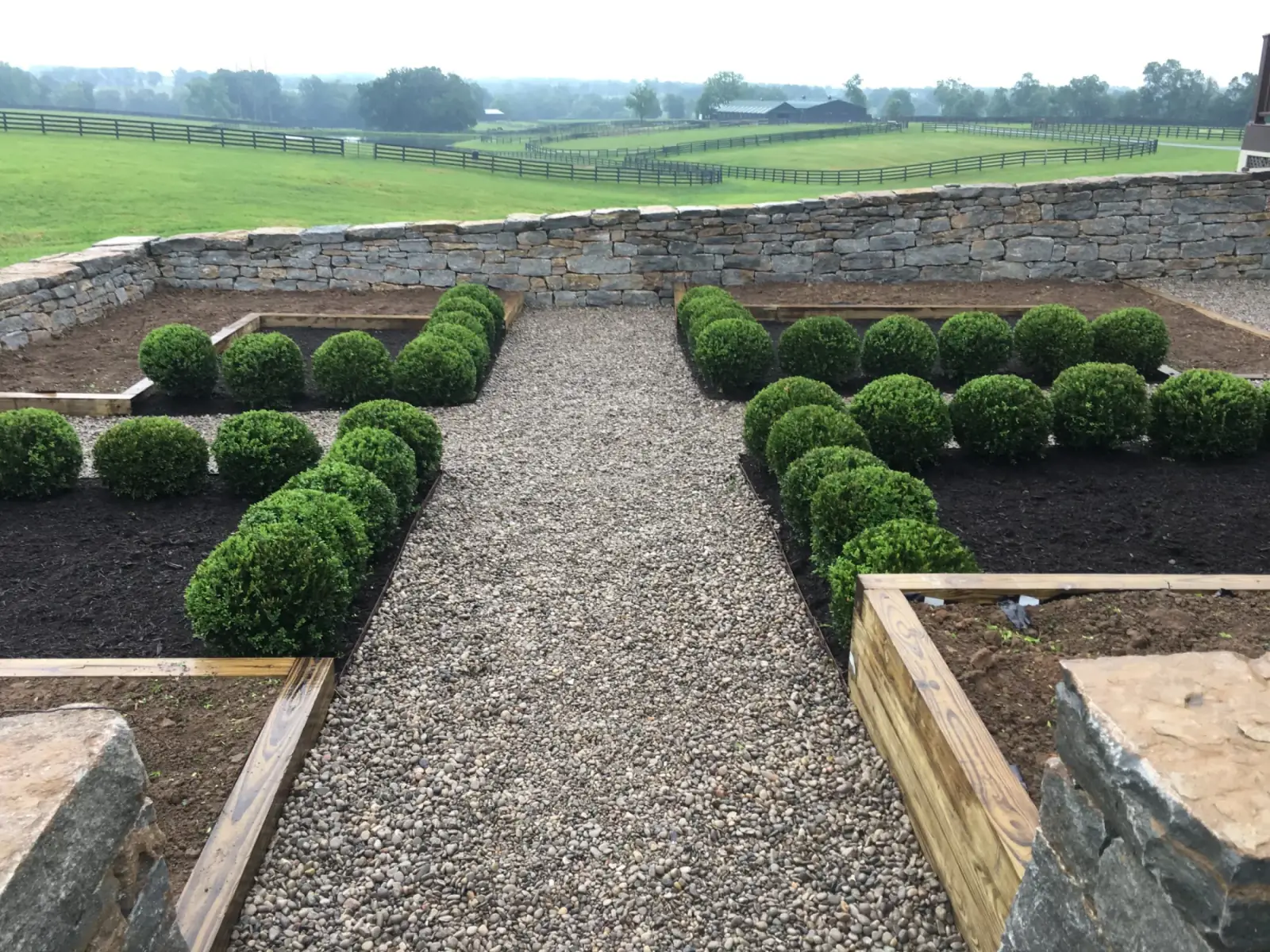 Finished Lexington walkway with shrub planting and wood-framed garden beds beside a home