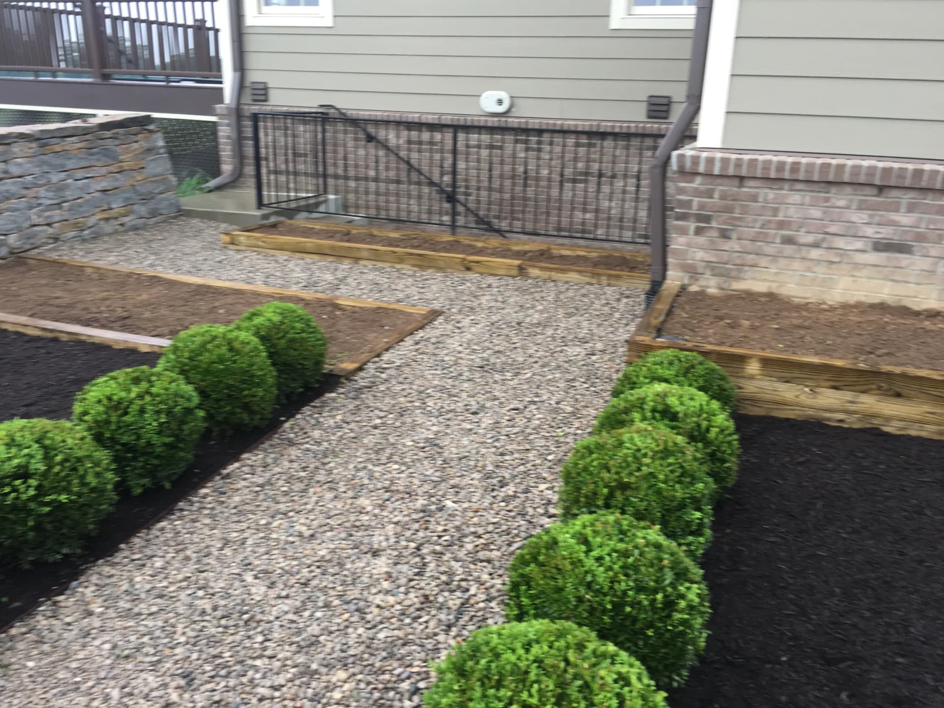 Wood-framed garden beds and gravel walkway beside a Lexington home